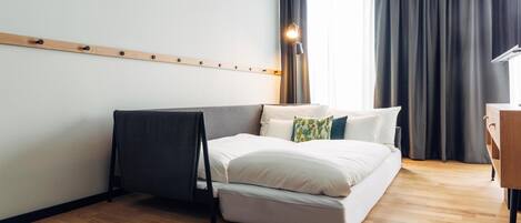 Una habitación de hotel moderna con una cama, un escritorio y una lámpara.