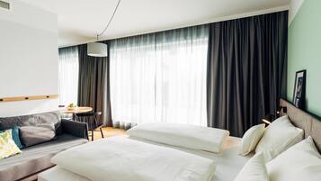 A hotel room with a bed, a sofa, a dining table, and a chair.