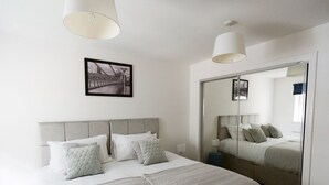 Ein modernes Schlafzimmer mit einem großen Bett, einem Spiegel und einem gerahmten Bild an der Wand.