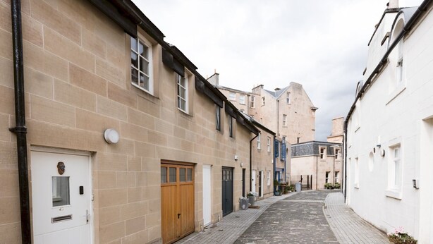 Eine schmale Kopfsteinpflasterstraße gesäumt von traditionellen Gebäuden, mit einer Mischung aus Holztüren und Metalltüren sowie verschiedenen Architekturstilen.