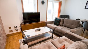 Ein Wohnzimmer mit Flachbildfernseher, zwei Sofas, einem Couchtisch und einem Essbereich mit Tisch und Stühlen.