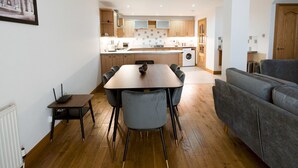 Eine moderne Küche mit Holzschränken, einem Esstisch mit Stühlen und einem grauen Sofa im Wohnbereich.