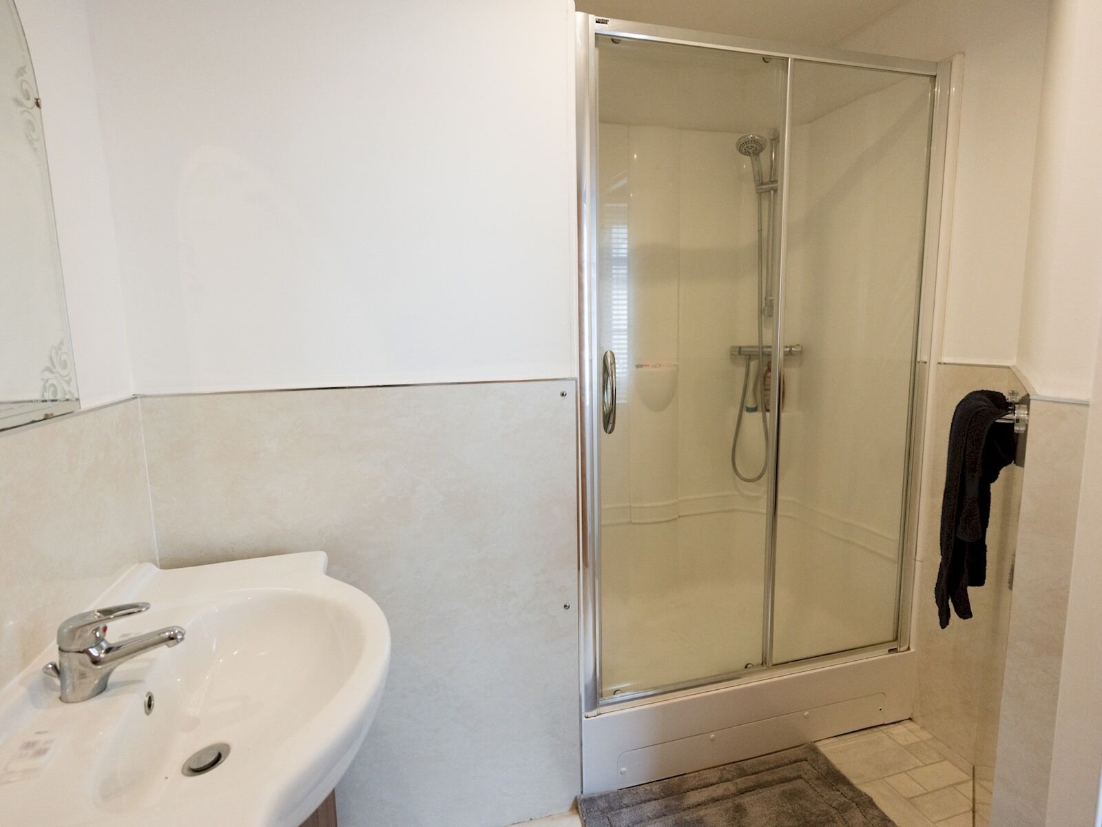A bathroom with a glass-enclosed shower, a sink, and a towel rack.