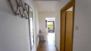 A hallway with a wooden floor, a table with a chair, and a door leading to another room.