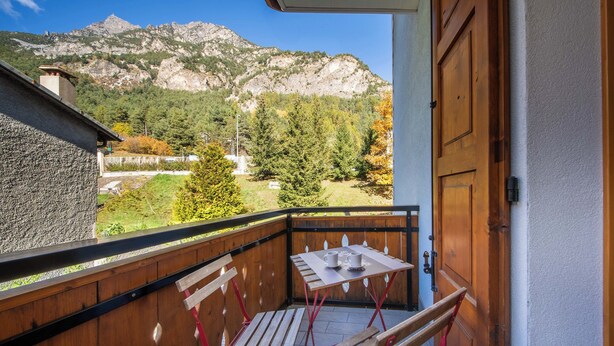 A balcony with a table and chairs, overlooking a mountainous landscape. - Italianway - Belvedere 28 (Valdidentro)