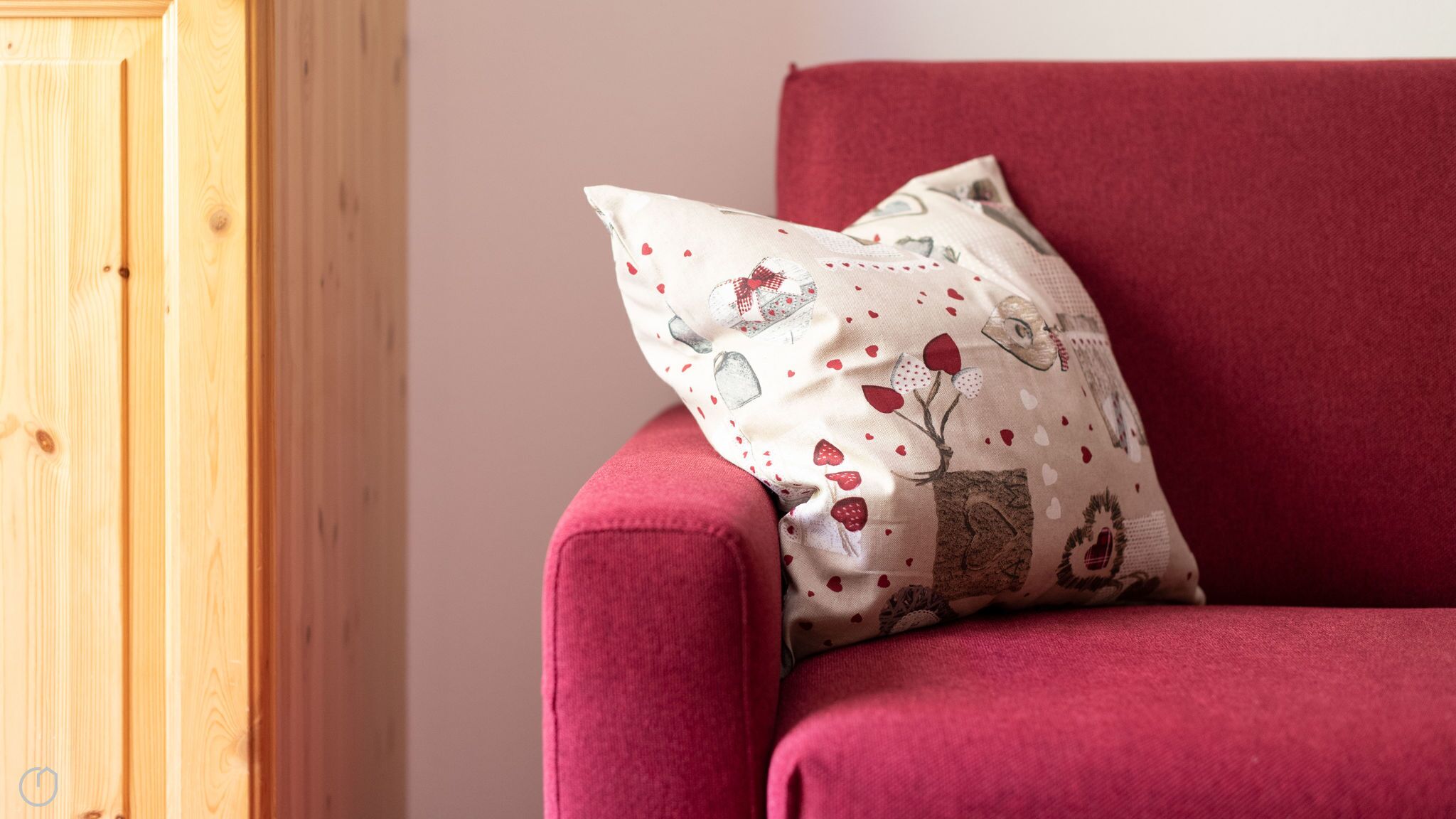 A red armchair with a decorative pillow featuring a floral pattern.