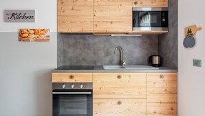 A modern kitchen with wooden cabinetry, a built-in microwave, a stainless steel sink, and a built-in oven. - Italianway - Belvedere 28 (Valdidentro)