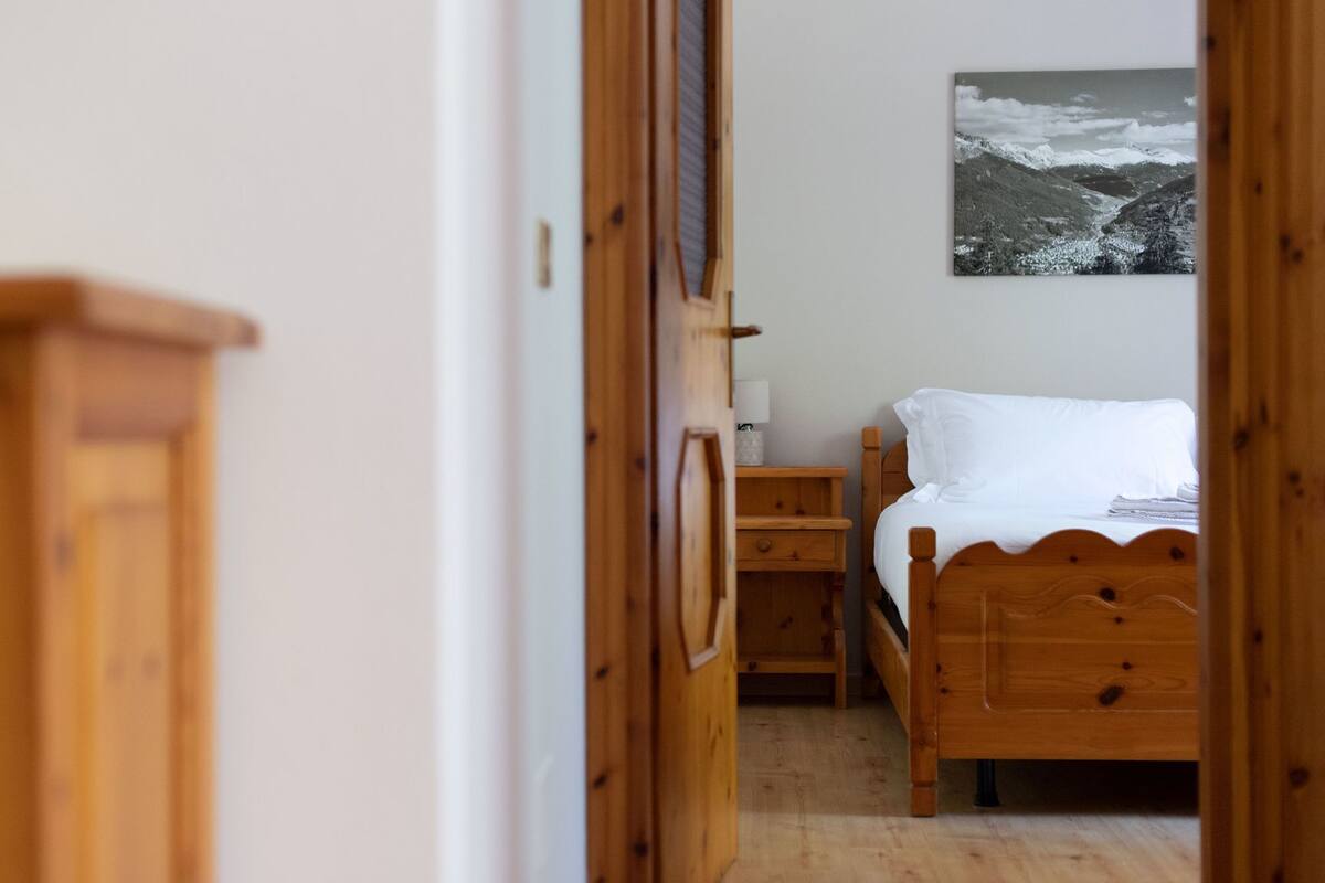 A bedroom with a wooden bed, a nightstand, and a wall-mounted lamp.