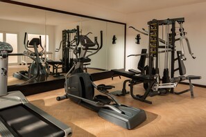 A gym with cardio machines, weightlifting equipment, and a mirrored wall.