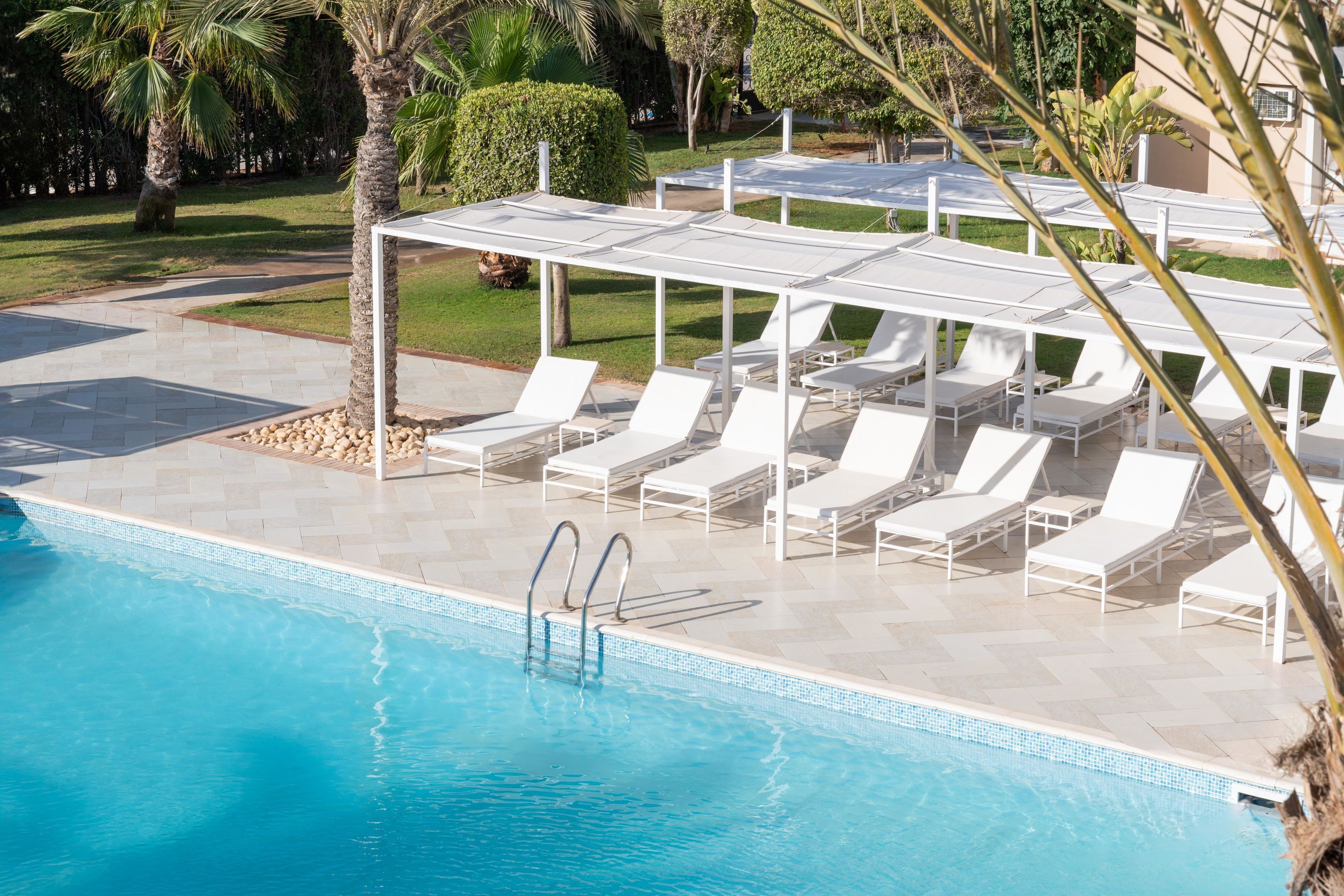 Una piscina al aire libre, sillones reclinables de piscina