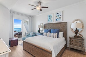 A bedroom with a large bed, a ceiling fan, a nightstand, a dresser, and a view of the ocean. - Adagio C301 | Gulf Front Condo | Private Beach Access | Resort Style Pool!! (Santa Rosa Beach)