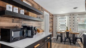 A modern kitchen with a coffee maker, tea and sugar containers, and a wooden wall. - Clearwtr10min2beach&2min2 Dunedindwtn/king bed (Clearwater)
