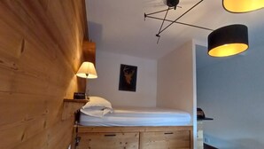 A wooden room with a bunk bed, a wall-mounted shelf, a lamp, and a framed picture. - Bright 30 M² With Balcony   Center Villa (Le Monêtier-les-Bains)