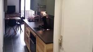 A modern kitchen with dark tiles, wooden cabinets, and a built-in oven. - Bright 30 M² With Balcony   Center Villa (Le Monêtier-les-Bains)