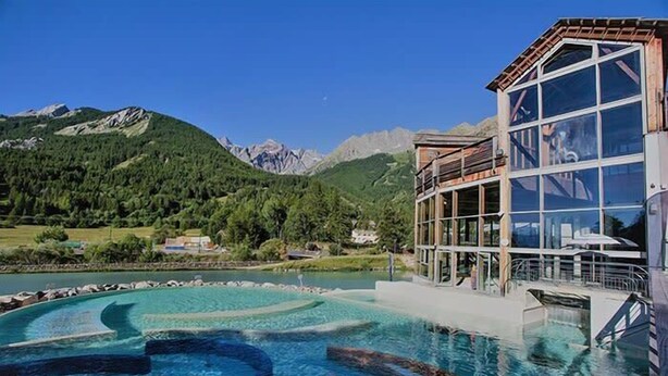 A hotel with a pool featuring a circular design, surrounded by mountains and greenery. - Bright 30 M² With Balcony   Center Villa (Le Monêtier-les-Bains)