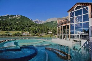 A hotel with a pool featuring a circular design, surrounded by mountains and greenery. - Bright 30 M² With Balcony   Center Villa (Le Monêtier-les-Bains)