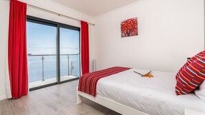 A bedroom with a large window, a bed with a striped pillow, and a red curtain.
