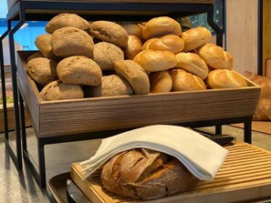 A display of various breads in a wooden box, with a loaf on a wooden board in front. - The Moss - Your unique hideaway (Soelden)