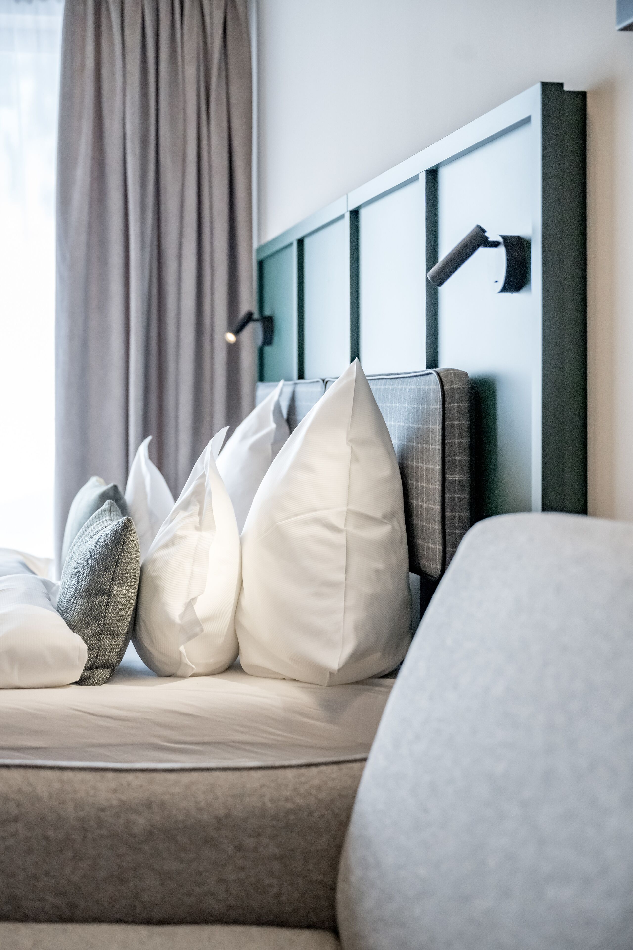 A neatly made bed with a headboard, pillows, and a bedside table.
