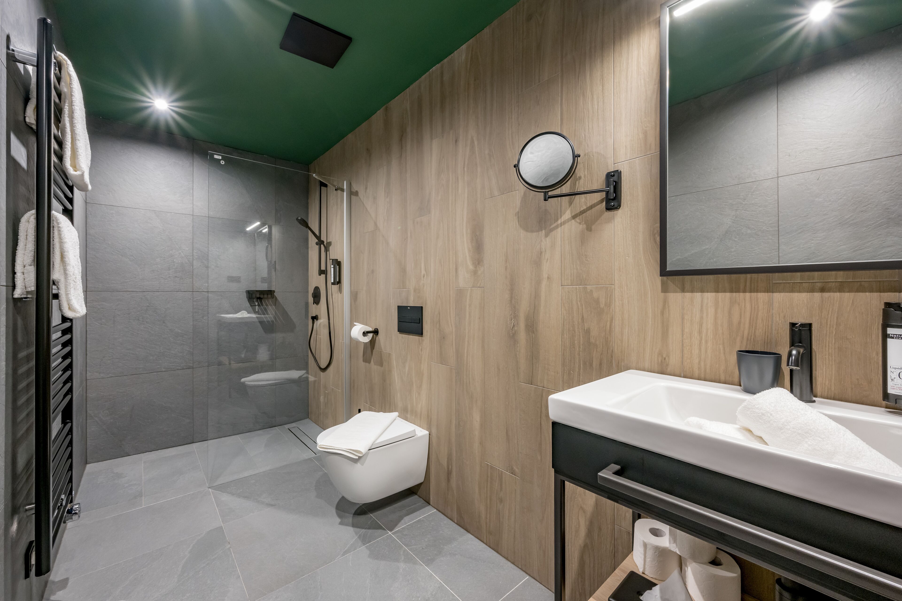 A modern bathroom with a large mirror, a sink, a toilet, and a shower area.