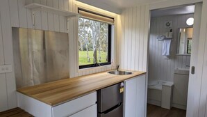 Uma cozinha compacta com bancada de madeira, pia de aço inoxidável e geladeira embutida.