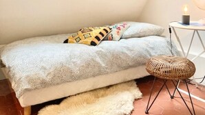 Un dormitorio tipo loft acogedor, con una cama, una mesita de noche con lámpara y un ventanal.