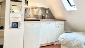 Una cocina compacta con armarios blancos, lavavajillas y una ventana sobre el fregadero.