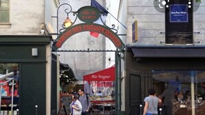 Escena callejera con un letrero que dice 'MARCHÉ DES ENFANTS ROUGES' y una tienda con el rótulo 'Bio Wagner'.