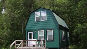 A green cabin with a wooden deck, two windows, and a door. - Maple Ridge Creek in the North Georgia Mountains (Morganton)