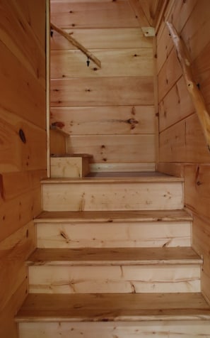 A wooden staircase with a handrail, leading to a landing with a small table.