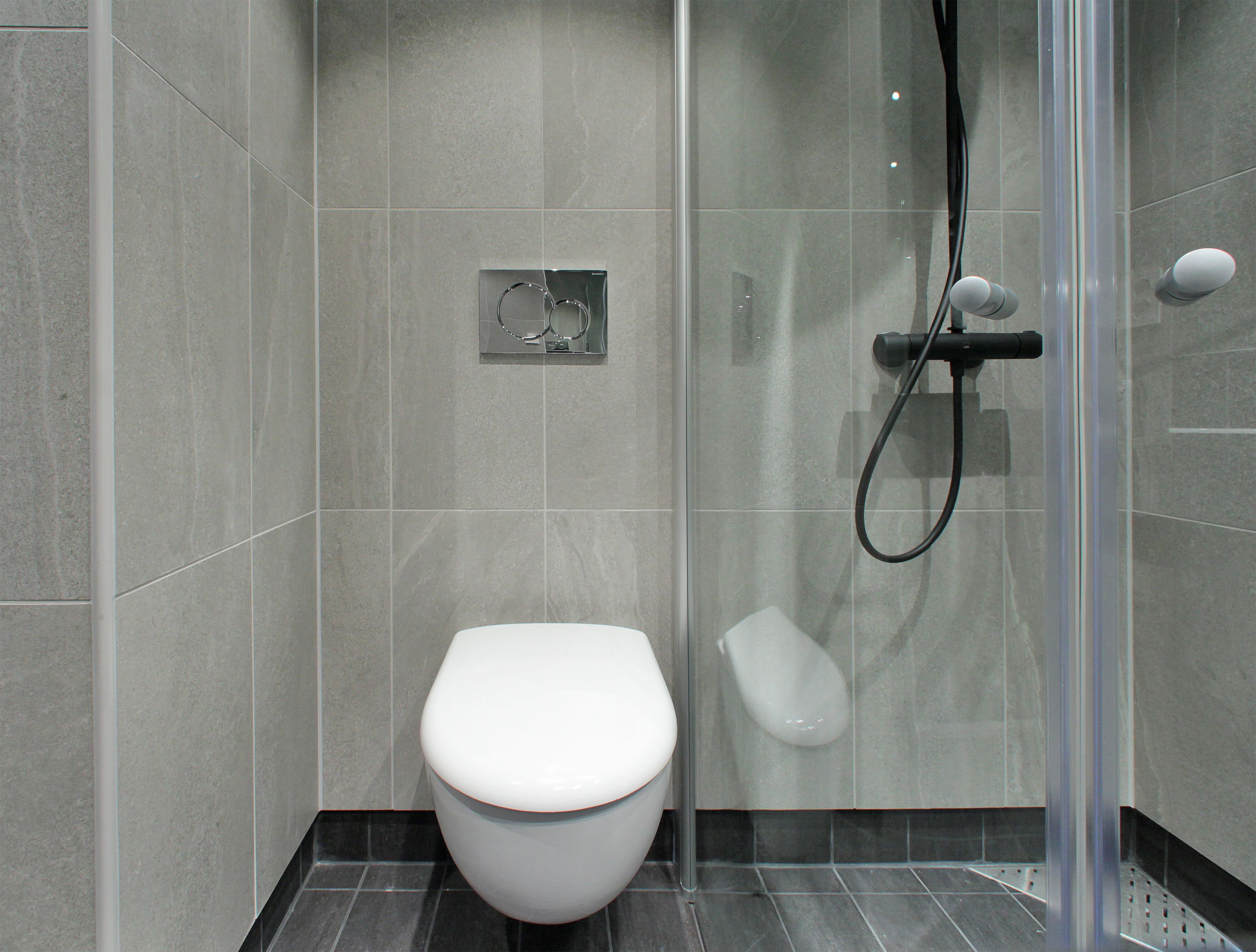 Un baño moderno con inodoro, cabina de ducha y mampara de vidrio.