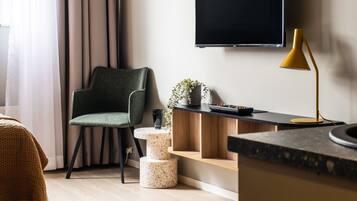 Un salon moderne avec un fauteuil vert, une table basse noire, un lampadaire jaune et un téléviseur à écran plat fixé au mur.