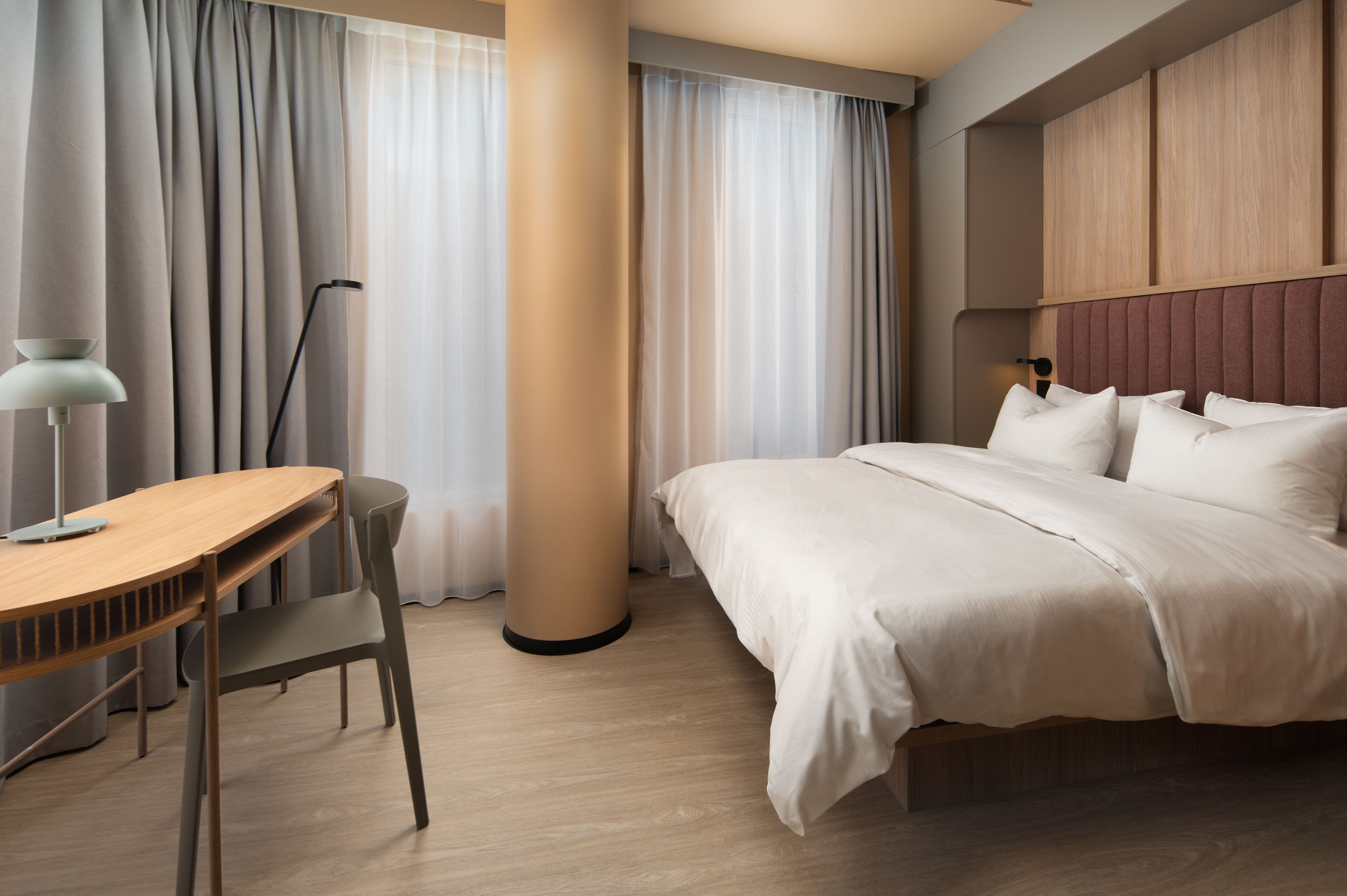 A hotel room with a bed, a desk, and a chair.