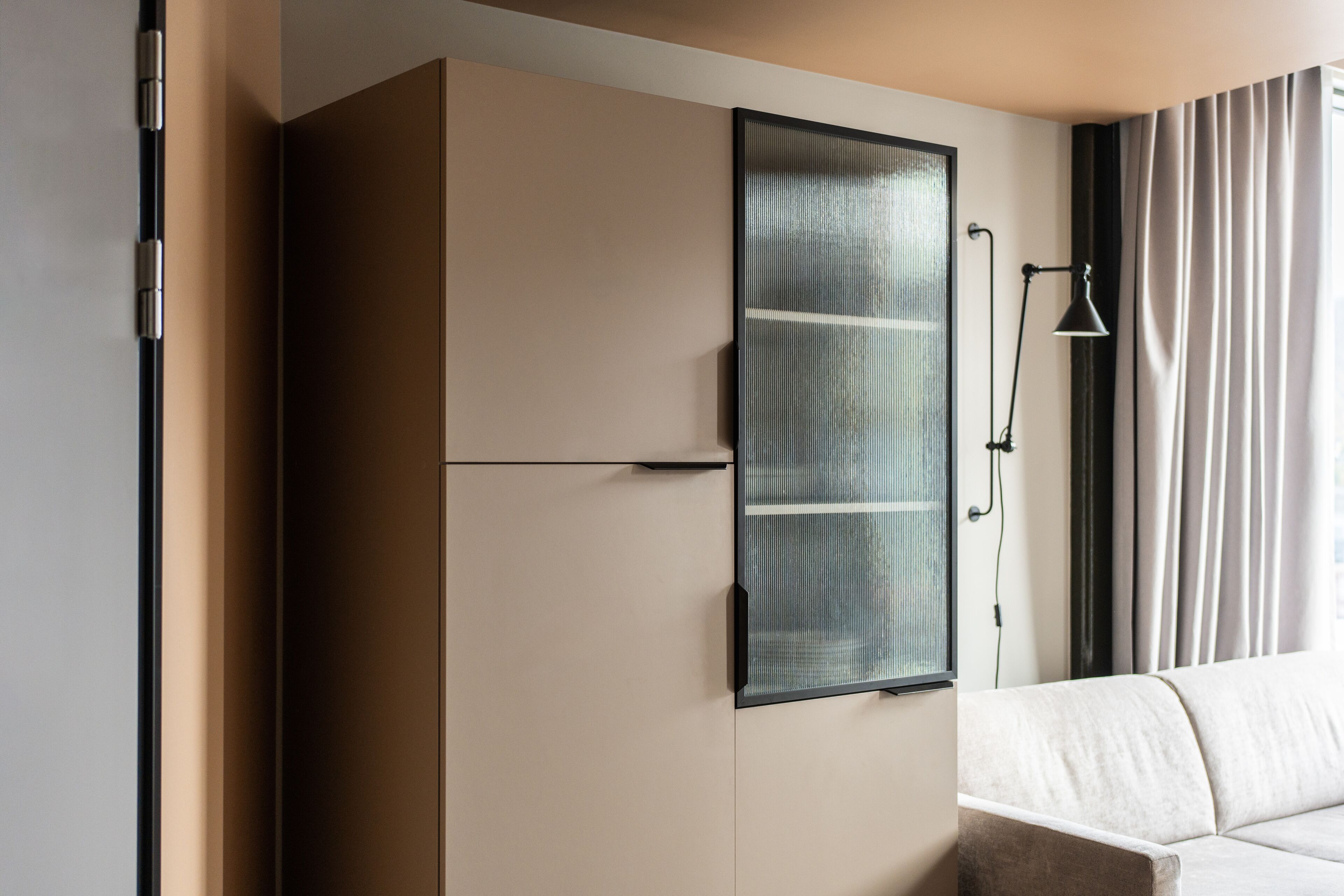 Ein modernes Zimmer mit integriertem Kleiderschrank, Nachttisch und Lampe.