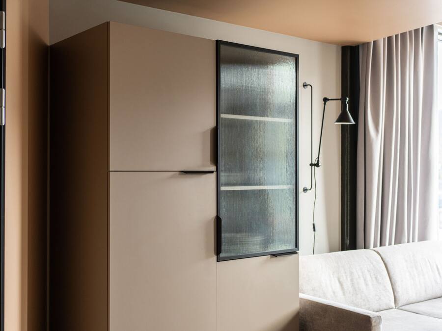 Ein modernes Zimmer mit integriertem Kleiderschrank, Nachttisch und Lampe.