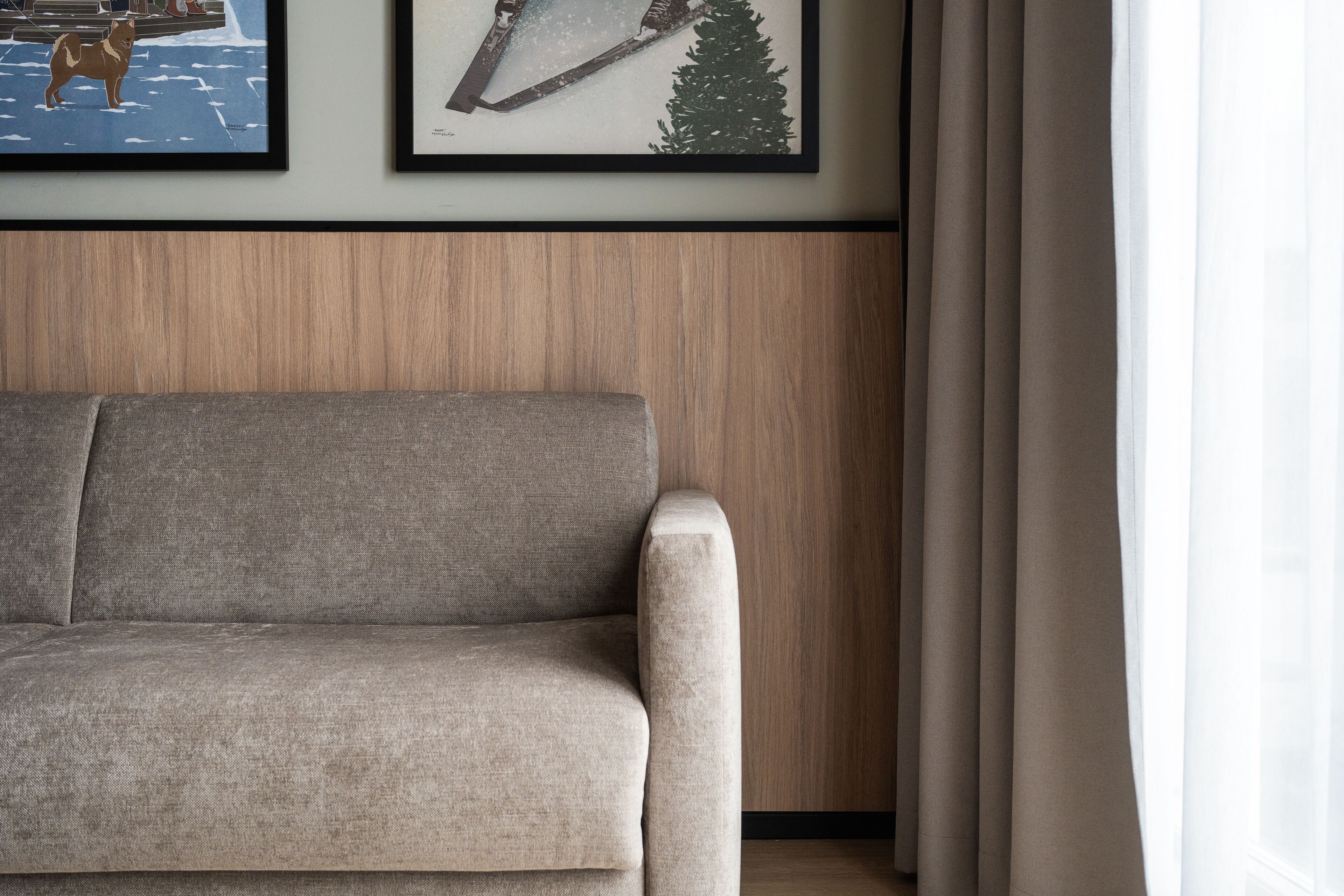 A modern living room with a sofa, framed artwork, and a wooden panel wall.