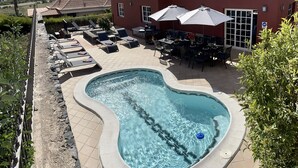 A swimming pool with lounge chairs and umbrellas, a patio area with tables and chairs, and a mountain in the background. - Spacious Villa in Quiet Location Close to Resorts (Buzanada)