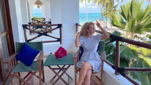 A balcony with a view of the beach, a table with a chair, and a decorative vase. - Five Palms Bwejuu (Bwejuu)