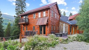 A log cabin with a balcony, a covered porch, and a gravel driveway. - Spacious 7BR Lodge with Mountain Views! (Breckenridge)