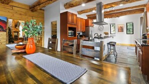 A spacious kitchen with wooden beams, a dining area with a long table, and a kitchen island. - Spacious 7BR Lodge with Mountain Views! (Breckenridge)