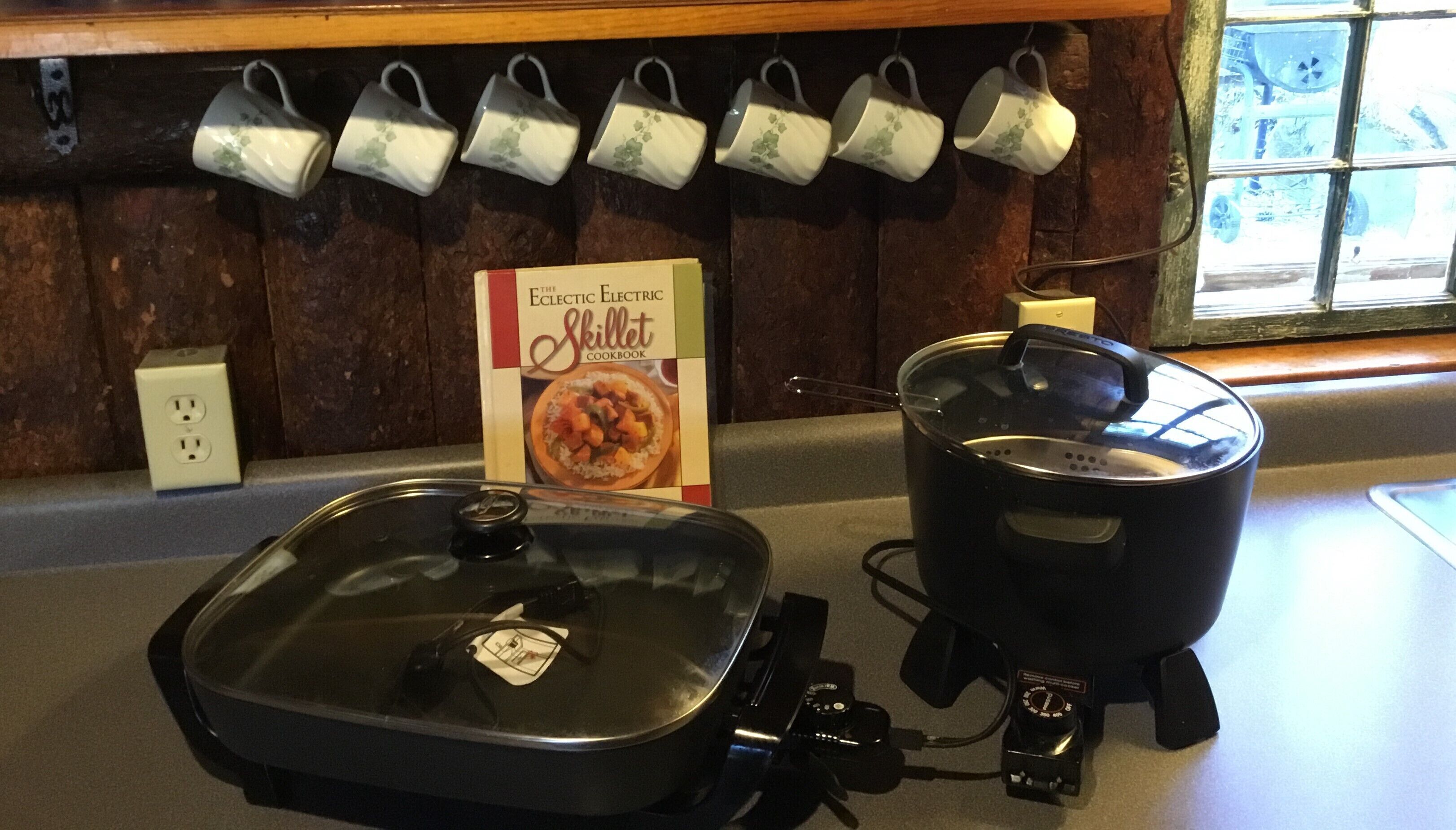 Una cocina con un hervidor, una olla y un libro de cocina sobre la encimera.