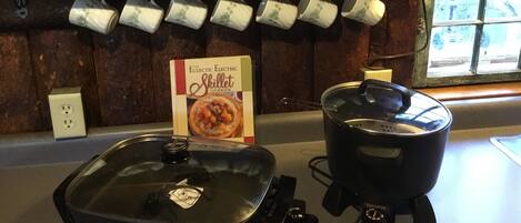 Una cocina con un hervidor, una olla y un libro de cocina sobre la encimera.