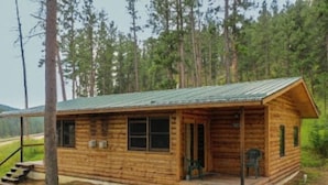 A wooden cabin with a porch, windows, and a door. - Timber Haven Cabins (Hill City)