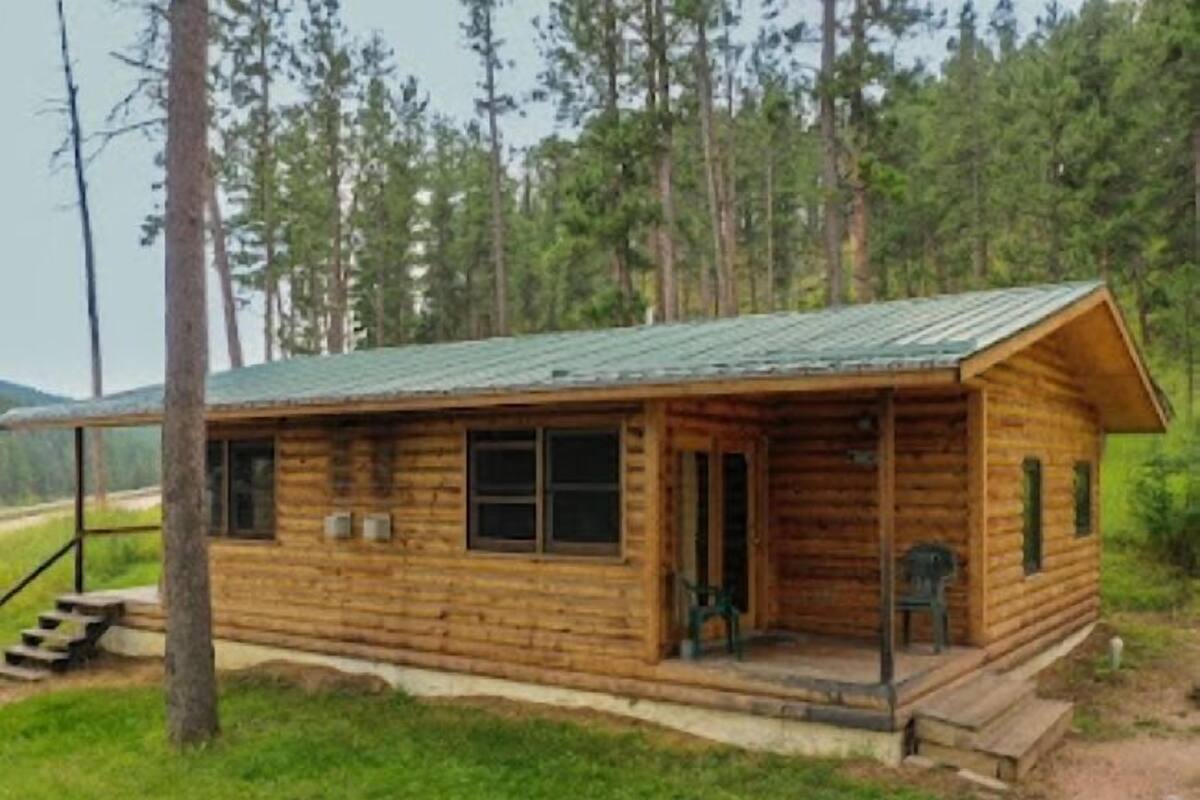 A wooden cabin with a porch, windows, and a door.