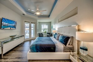 Um quarto moderno com uma cama grande, um ventilador de teto e vista para o exterior pela porta.