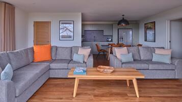A living room with two grey sofas, a wooden coffee table, and a view of a kitchen and dining area.