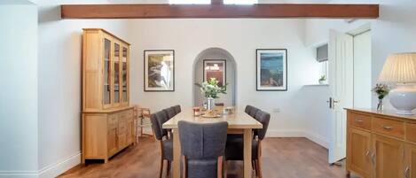 A dining area with a wooden table and chairs, a wooden cabinet, and framed pictures on the wall.