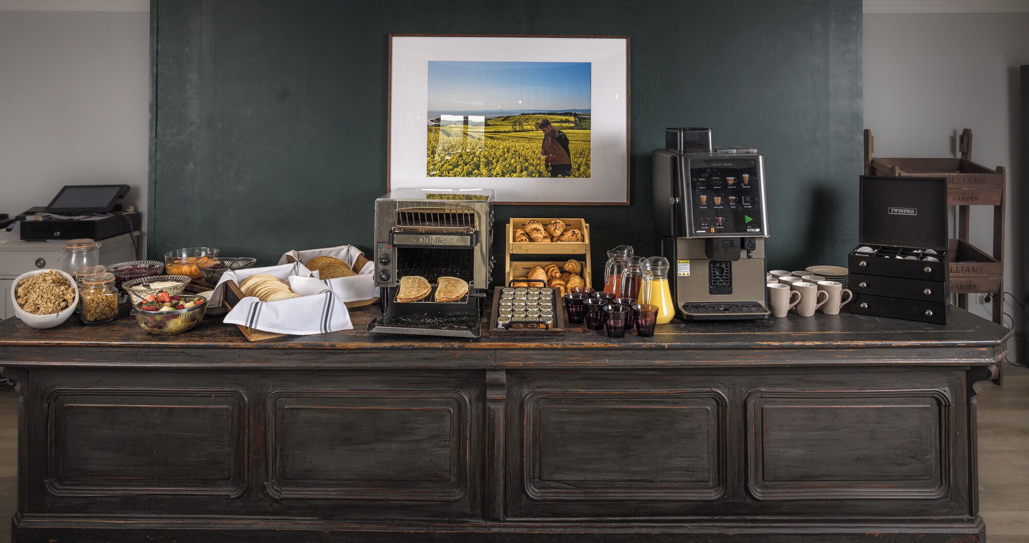 A kitchen counter with a coffee machine, a bread oven, and various food items.