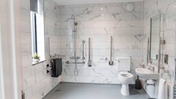 Un bagno moderno con WC, lavabo e zona doccia, caratterizzato da piastrelle in marmo e accessori cromati.
