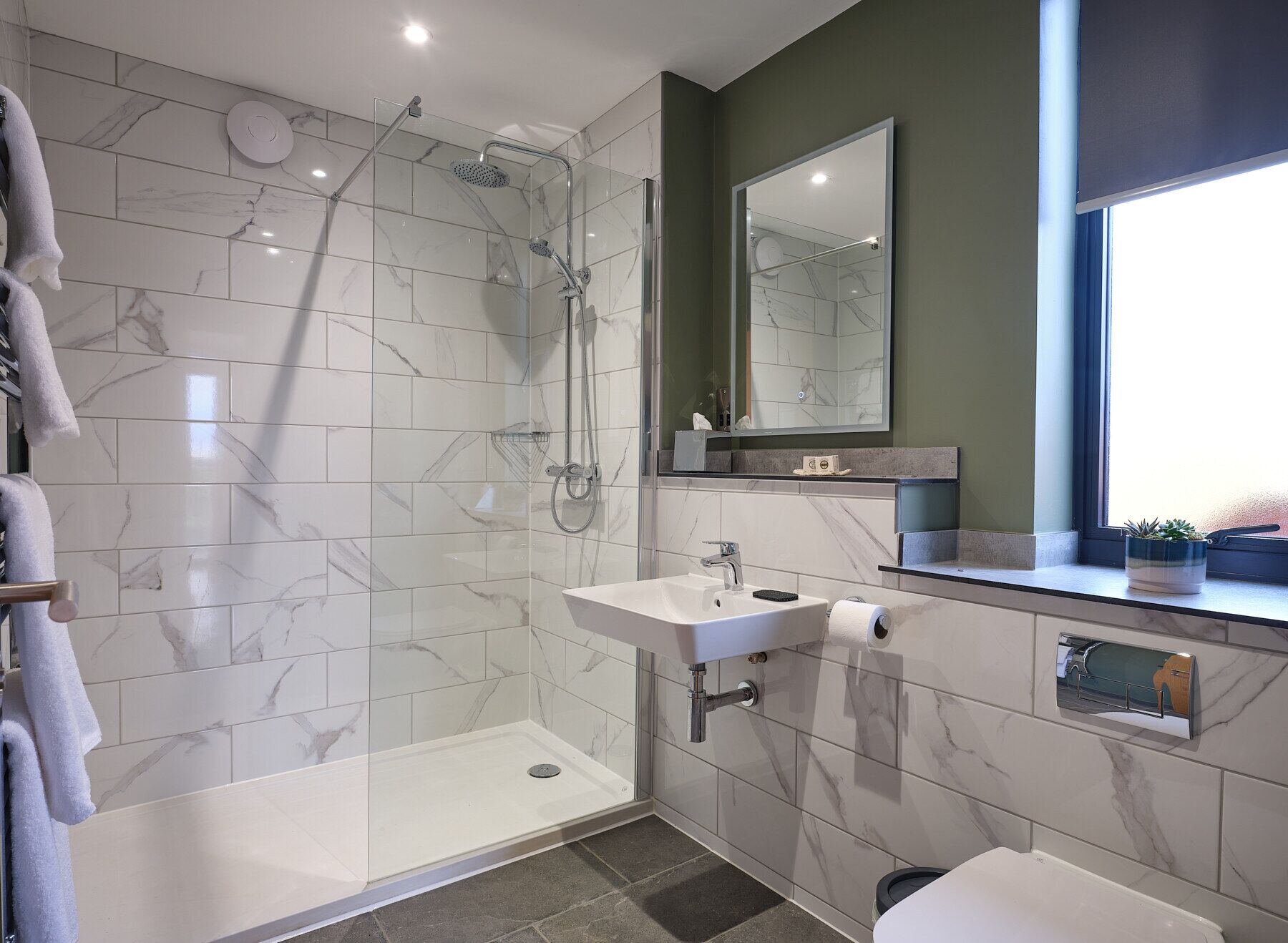 Une salle de bain moderne avec une douche à parois de verre, un lavabo avec un miroir au-dessus et des toilettes.